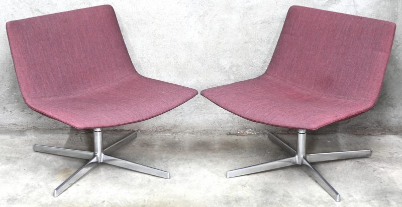 “Catifa 80”. Een paar design lounge draaistoelen met rood gestoffeerde zitting en gechromeerde X-voet. Ontwerp door Lievore Altherr Molina voor Arper.