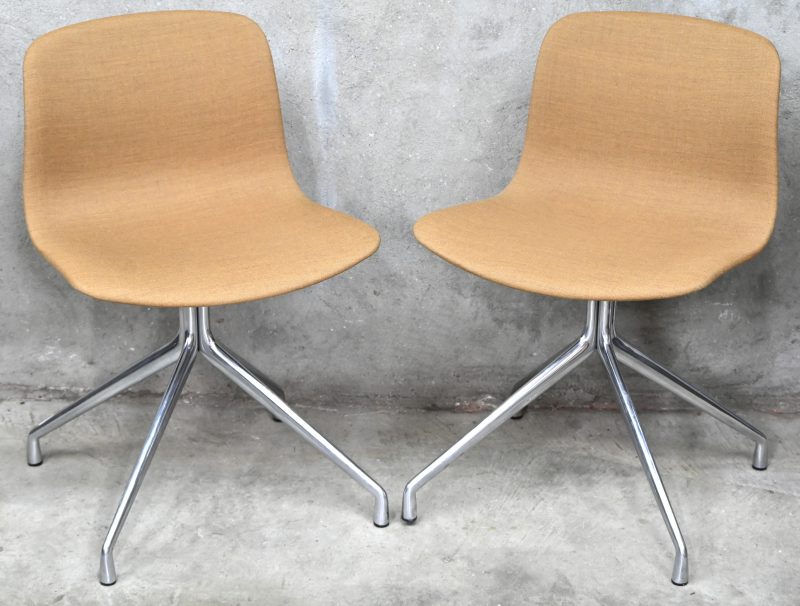 “Model AAC 11”. Een paar design draaistoelen met oranjebruin gestoffeerde zitting en gechromeerd aluminium X-onderstel. Ontwerp door Hee Welling voor HAY.
