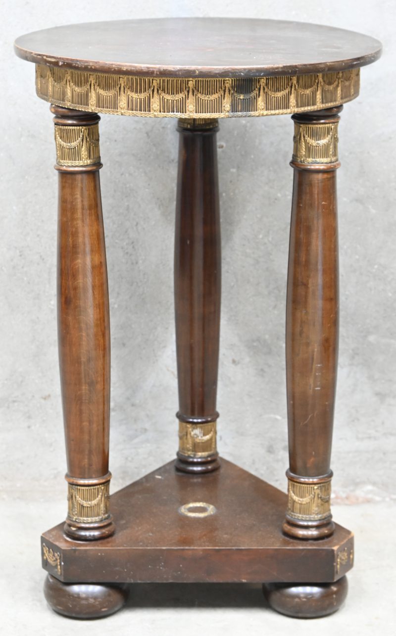 Een antiek houten bijzettafeltje in Empire stijl met rond blad en diverse bronzen elementen versierd.%