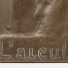Een bronzen plaquette met opschrift L’aleule en gesigneerd C. Devrees.
