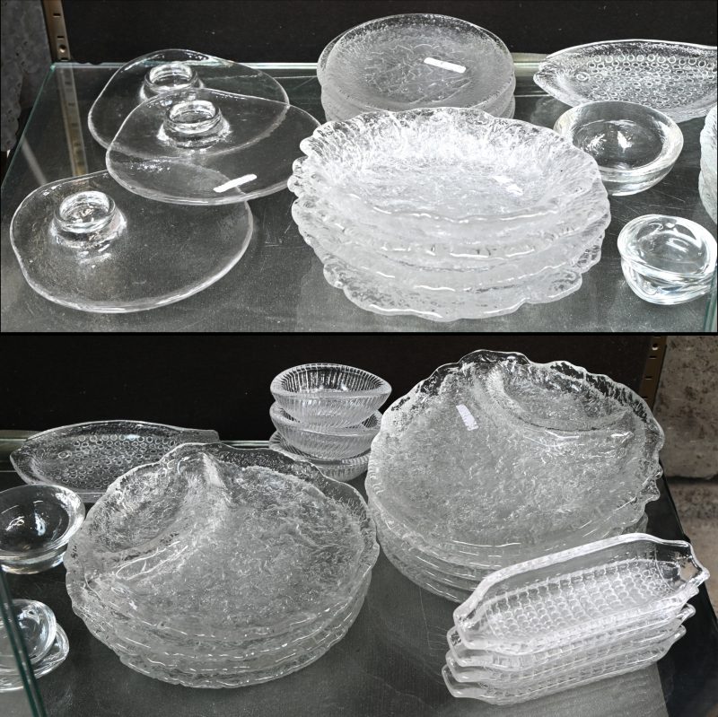 Een kleurloos ‘frosted’ glazen vintage servies. Bestaande uit: 10 borden met vak, 4 diepe schalen, 6 kaaschotels, een schotel in de vorm van een vis, 4 maisvormige schaaltjes, en 9 andere.