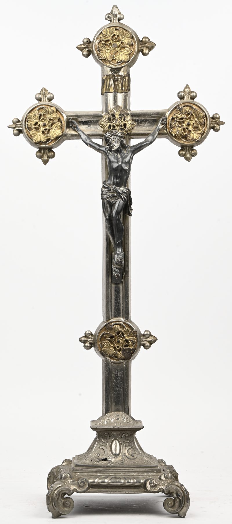 Een verzilverd metalen crucifix met vergulde elementen.