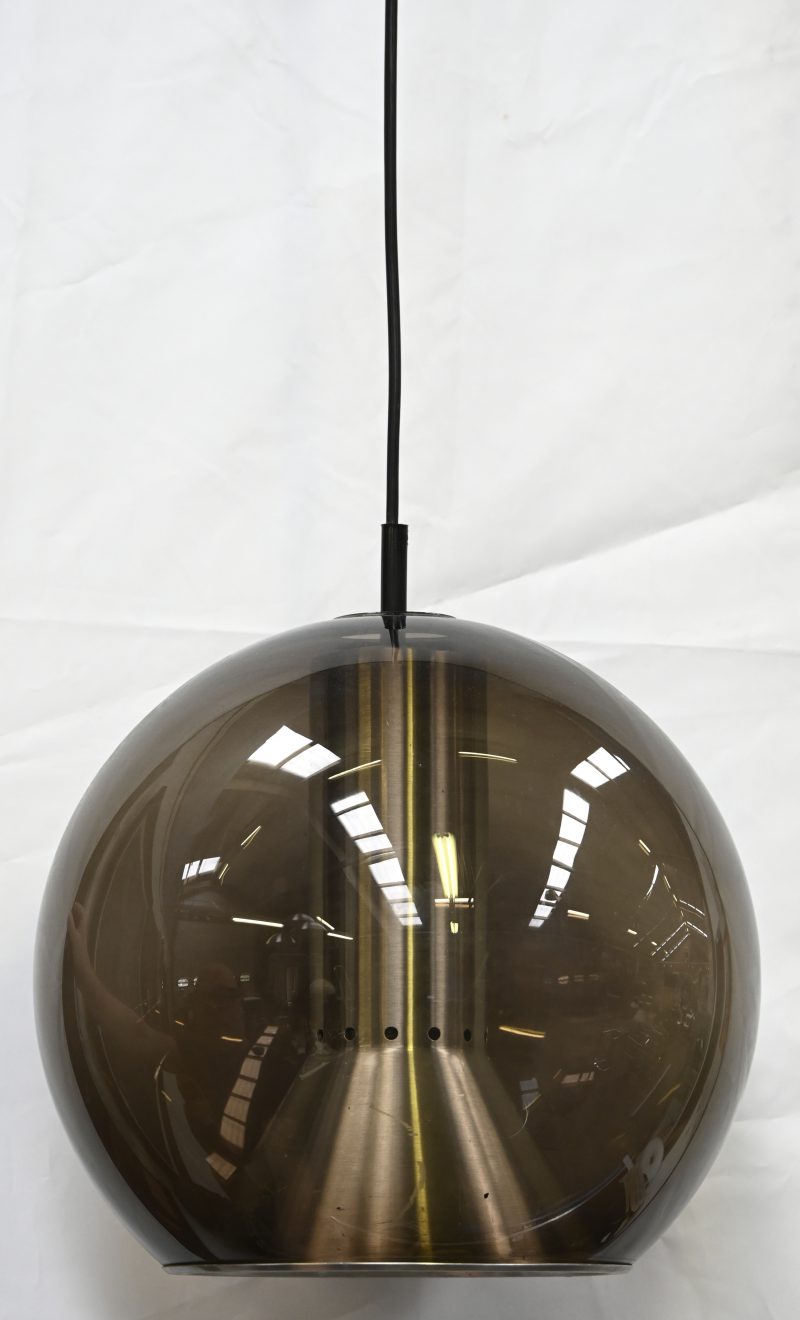 “Globe hanger”. Een vintage design hanglamp met smoked glazen bol en aluminium reflector. Ontwerp uit de Globe-serie door Frank Ligtelijn voor Raak, Nederland. Fabrikage van het glas door Peill & Putzler, Duitsland. Binnenin gemerkt.