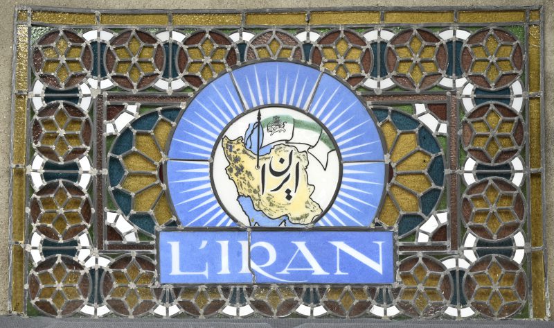 “L’Iran”, een glas-in-loodraam met landkaart en vlag van Iran afgebeeld. Kleine schade aan glas en lood.