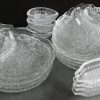 Een kleurloos ‘frosted’ glazen vintage servies. Bestaande uit: 10 borden met vak, 4 diepe schalen, 6 kaaschotels, een schotel in de vorm van een vis, 4 maisvormige schaaltjes, en 9 andere.