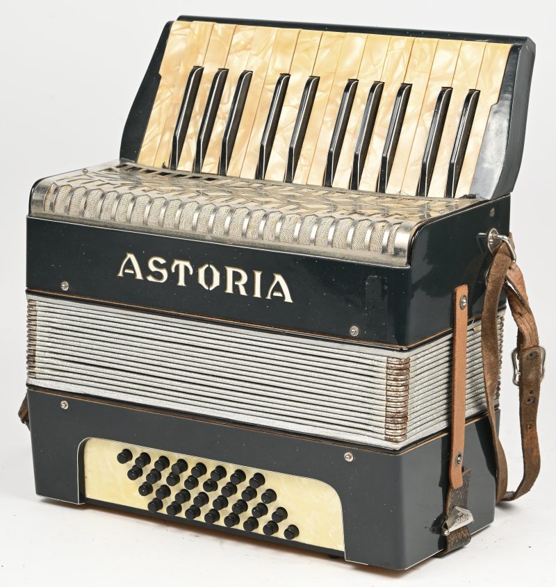 Een antieke accordeon, van het merk Astoria met toetsen in parelmoer, in zijn originele koffertje.