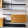 “String Bokhyllan, the Ladder Shelf”, een modulair wandsysteem bestaande uit 8 muur (ladder) elementen, 1 onderhangend rooster, 3 kastjes, 1 lange diepe schabbe, 3 lange ondiepe schabben, 3 korte diepe schabben en 3 korte ondiepe schabben.