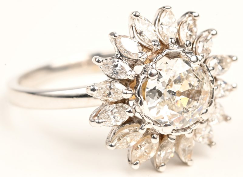 Een 18 kt witgouden ring bezet met een centrale diamant van +-1 ct. en diamanten marquise cut met een gezamenlijk gewicht van +- 1 ct.