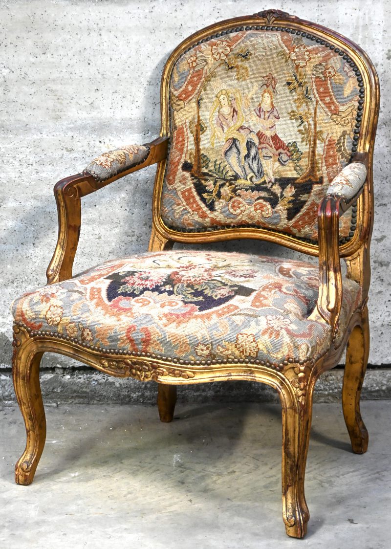 Een armstoel in Louis XV stijl, verguld hout en gobelin bekleding.