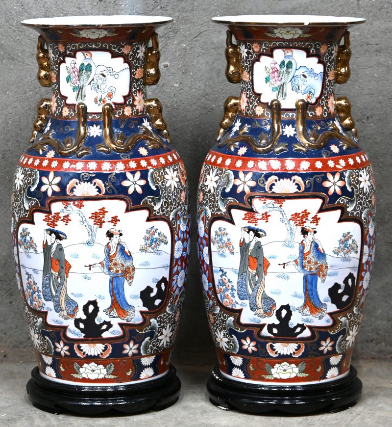 Een paar grote vintage Chinees porseleinen vazen met figuratief decor en vergulde ornamenten. Op bijhorend houten sokkels.