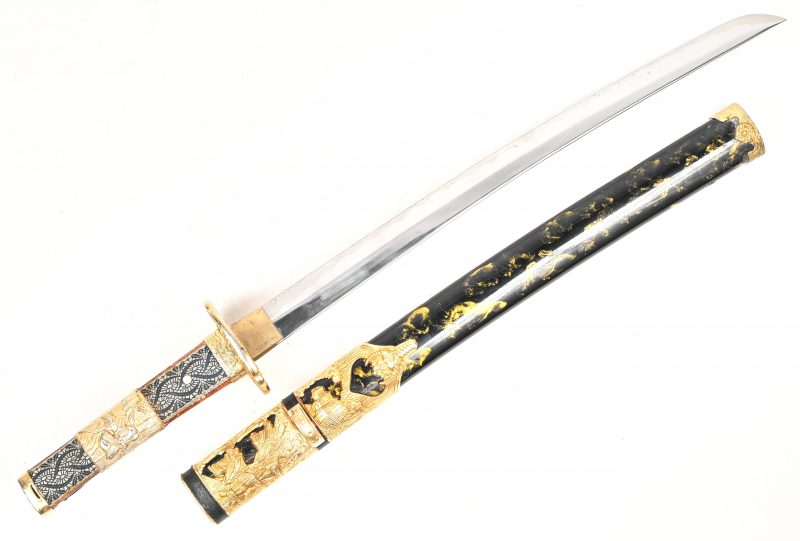 Een Japans Samurai wakizashi of kortzwaard replica met krijgstafereel in het verguld reliëf.