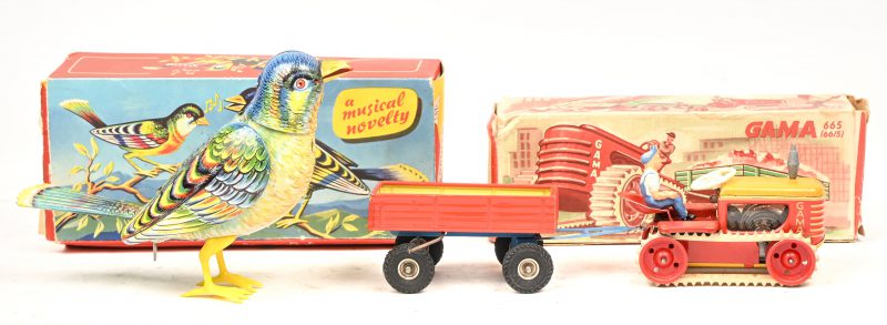 “Gama 665”, een vintage tin toy tractor met rupsbanden en aanhangwagen, in originele doos. En “A musical novelty”. Een vintage tin toy zangvogeltje, in originele doos met enige schade. 1 klauwtje aan de poot afgebroken.