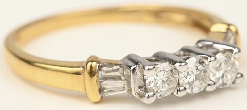 Een 18 kt wit- en geelgouden ring bezet met briljanten en diamant baguetten  met een gezamenlijk gewicht 0,52 ct.