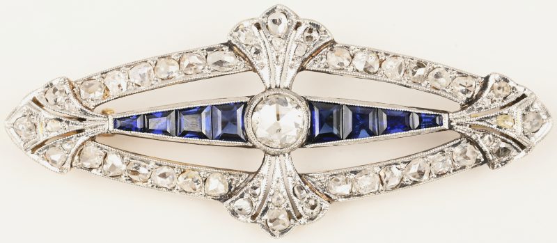 Een 18 kt wit en geelgouden broche bezet met diamanten oude slijp met een gezamenlijk gewicht van ± 1 ct.  en met saffier baguettes met een gezamenlijk gewicht van ± 0,60 ct.