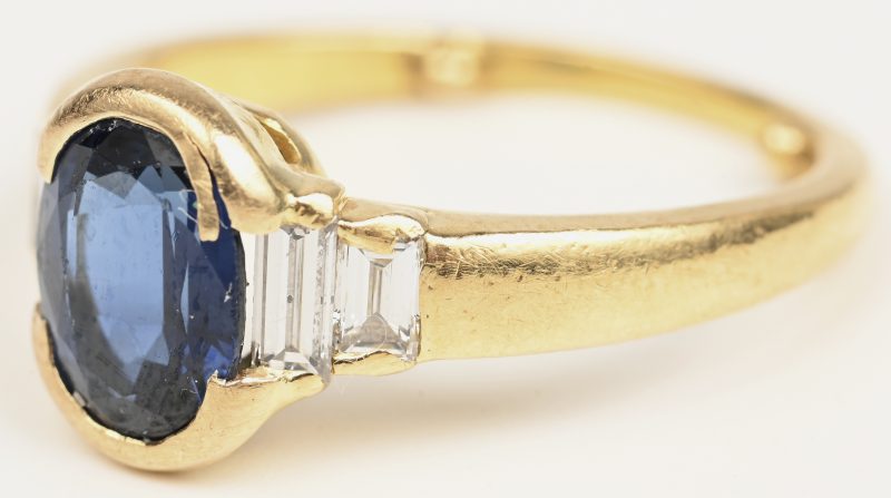 Een 18 kt geelgouden ring bezet met een centrale saffiet van +- 1 ct. en diamant baguetten met een gezamenlijk gewicht van +-  ct.