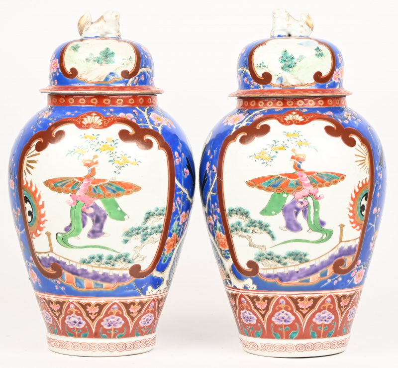 Een paar polychrome Chinees porseleinen vazen. Met decor van figuur en vleugels en vogels. Fo-honden als dekselknop. Eén vaas met restauratie aan de bovenrand.