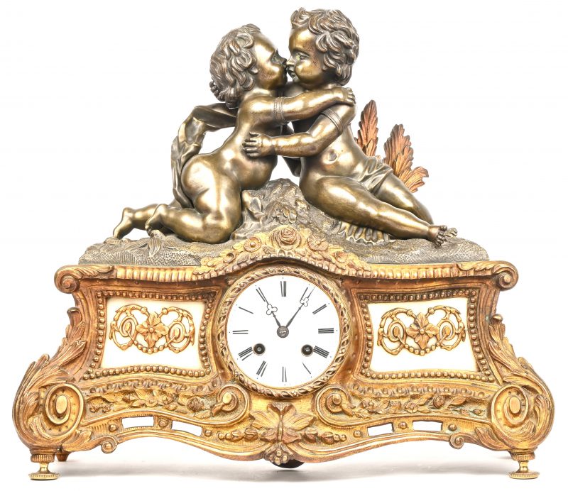 Een schouwpendule in brons en messing met 2 Putti in innige omhelzing.