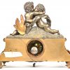 Een schouwpendule in brons en messing met 2 Putti in innige omhelzing.