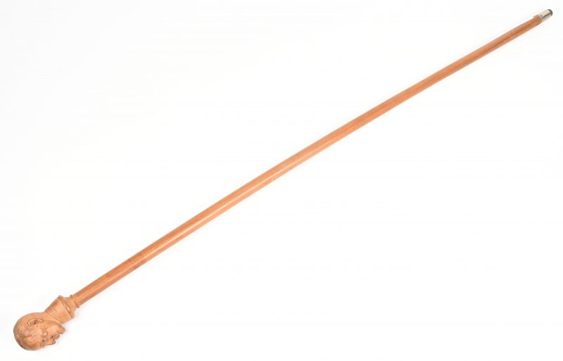 Een houten wandelstok met houtgesculpteerde kop.
