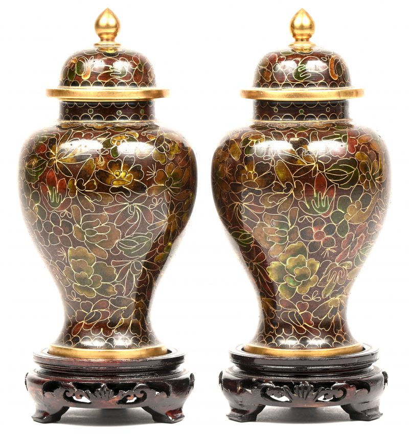 Een set van 2 dekselvaasjes in cloisonné op houten sokkeltje, Chinees werk. 1 dekseltje heeft binnenin schade.