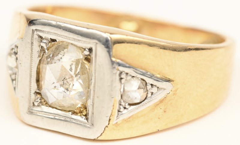 Een 18 kt wit en geelgouden herenring bezet met een centrale diamant oude slijp van +- 0,50 ct. en twee kleine  diamantjes oude slijp.