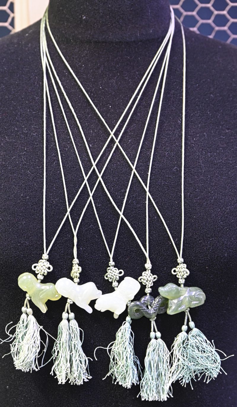 Vijf verschillende Chinese jade beeldjes als hangers met geweven koorden.