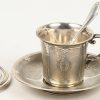 Een lot zilver bestaande uit een tas met ondertas met opschrift ‘Arnold’, een beker, een eierdopje met lepel en het opschrift ‘Guy’, 2 servetringen, een doosje met lepel en vork en 2 doosjes met serveerbestek waarvan enkel de heften in zilver.