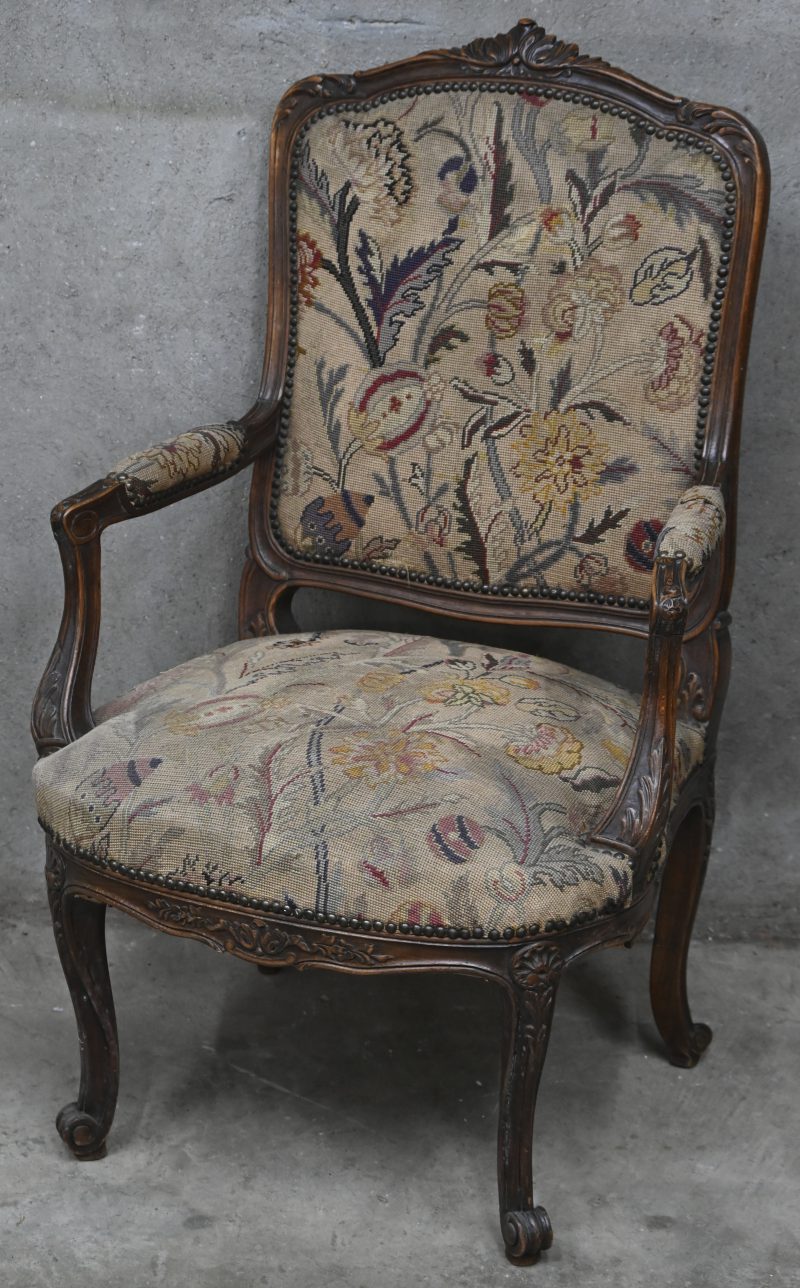 Een donker gebeeldhouwde eikenhouten armstoel, Louis XV stijl, Gobelin bekleding met florale motieven.