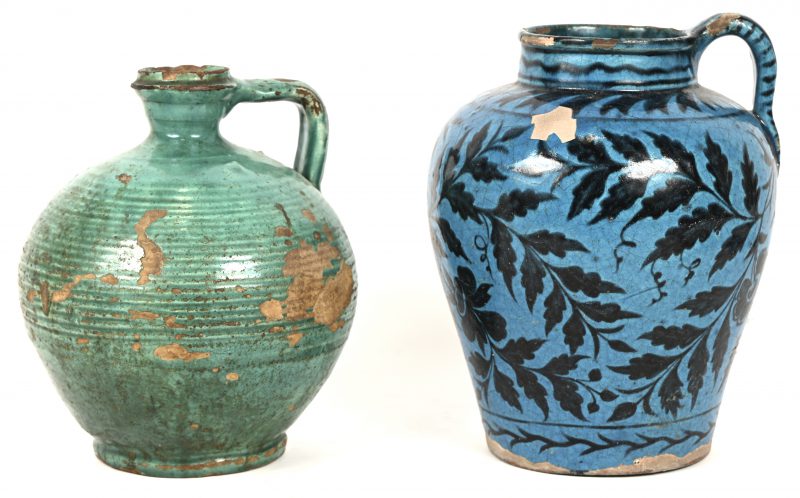 Een lot van 2 antieke geglazuurd aardewerken kannen, de ene blauw met bladeren in het decor, de andere blauw-groen. Beide met randschade en beschadigd glazuur.