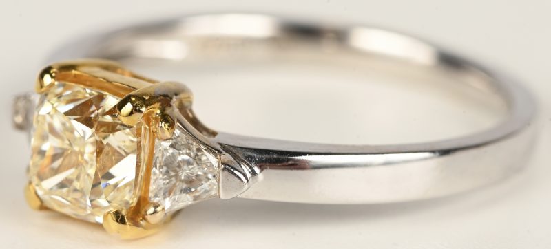 Een 18 kt wit en geelgouden ring bezet met centrale briljant van +- 0,70 ct. en briljanten met een gezamenlijk gewicht van +- 0,26 ct.