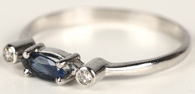 Een 18 kt witgouden ring bezet met twee kleine briljantjes en een saffier van +- 0,10 ct.