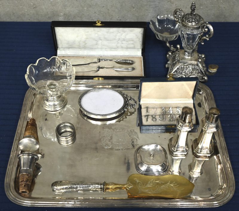 Een lot massief zilver en verzilverd metaal w.o. een fotolijstje met Nederlandse keur, een reeks plaatsnummer (niet compleet), stoppen, handvaten, zoutvat met kristal, voet met Nederlandse keur, een specerijenhouder met kristal (één bakje manco), een taartschep, een dessertbestek (800/1000), een grote rechthoekige plateau van verzilverd metaal met gegraveerd wapen van de familie Cartuyvels. E.a.