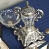 Een lot massief zilver en verzilverd metaal w.o. een fotolijstje met Nederlandse keur, een reeks plaatsnummer (niet compleet), stoppen, handvaten, zoutvat met kristal, voet met Nederlandse keur, een specerijenhouder met kristal (één bakje manco), een taartschep, een dessertbestek (800/1000), een grote rechthoekige plateau van verzilverd metaal met gegraveerd wapen van de familie Cartuyvels. E.a.