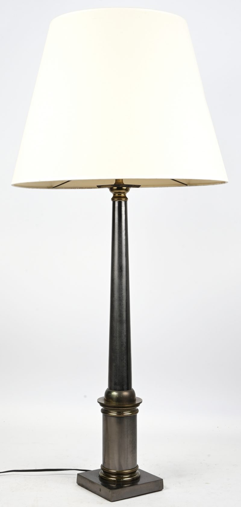 Een schemerlamp in de vorm van een moderne zuil in tweekleurig metaal.