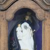 Een massief eikenhouten wandvitrine met hierin een wassen Madonna en kind.