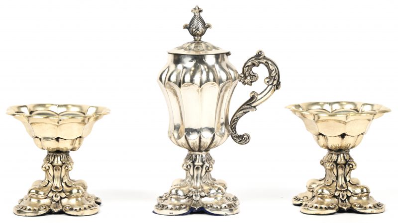 Drie verzilverde decoratieobjecten bestaande uit 2 kelkjes en een kleine schenkkan met gescharnierd deksel. Gestempeld in de voet.