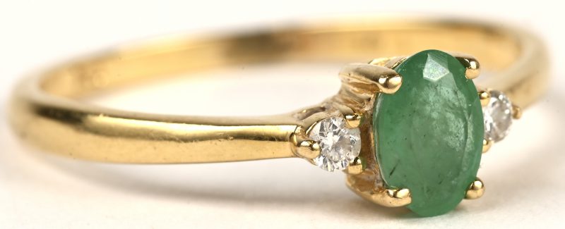 Een 18 kt geelgouden ring bezet met een Colombiaanse smaragd van +- 0,30 ct. en twee briljantjes.