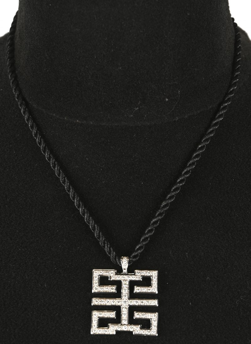 Een 18 kt witgouden hanger bezet met briljanten met een gezamenlijk gewicht van +- 0,71 ct. Met zwarte koord. Naar een model van Cartier.