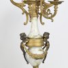 Bronzen mantelklok in barokke stijl met vergulde delen, slinger en glas manko. Toegevoegd een paar 6 armige kandelaars, waarvan telkens één arm manko.