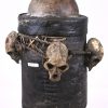 Afrikaans tribaal object bestaande uit een lederen ‘emmer’ op benen, gedecoreerd met apenschedels en de snavel van een hoornvogel. Op het deksel een koperen zonnemasker.