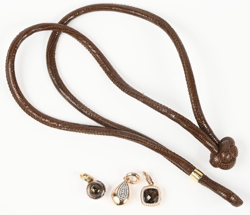 Een lederen halssnoer met twee 18 kt geelgouden hangers bezet met briljanten met een gezamenlijk gewicht van +- 0,40 ct. en één hanger van zilver en goud en rookkwarts.