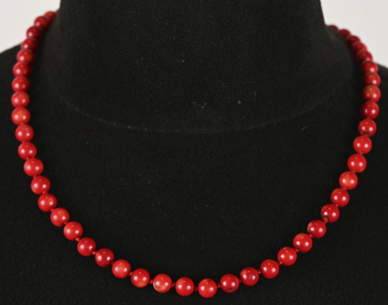 Een parelhalssnoer van rood koraal met zilveren veiligheids ketting.