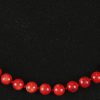 Een parelhalssnoer van rood koraal met zilveren veiligheids ketting.