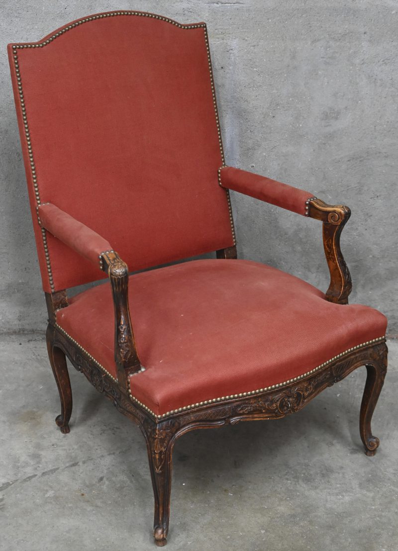 Een fauteuil à la reine van gebeeldhouwd notenhout, Régencestijl. Herbekleed met steenrode stof. XIXde eeuw.