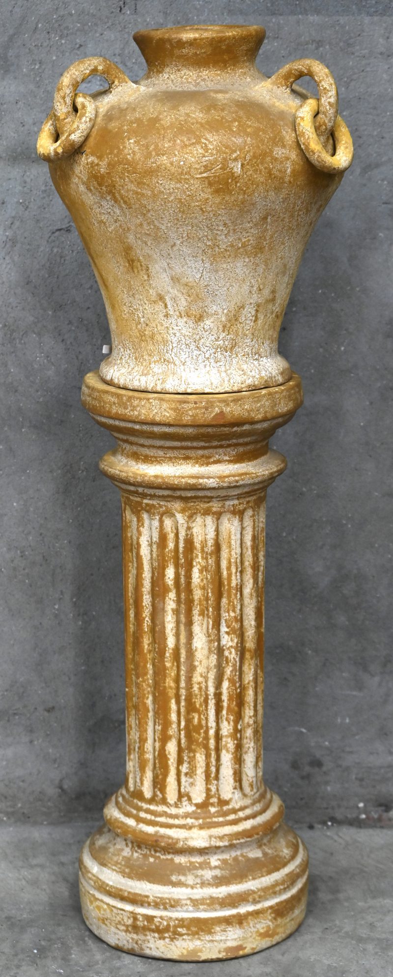 Een jardinière in terracotta, onderaan de vaas een herstelling.