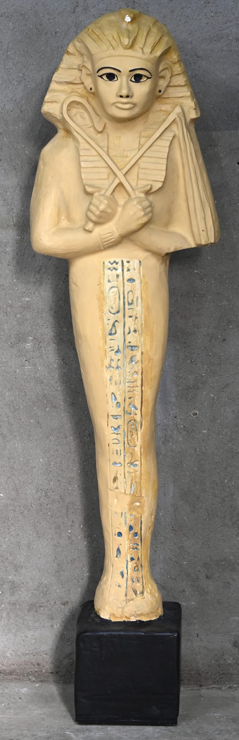 Gipsen beeld van Farao Ramses II met hiërogliefen, op zwarte sokkel.