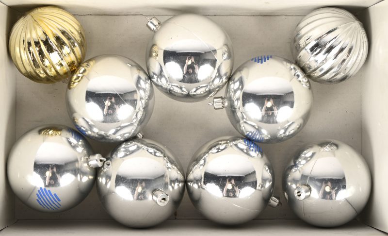 Een reeks van zeven zilverkleurige kerstballen en twee andere.