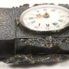 Een horlogehouder van zilver met Hollandse keuren (tweede gehalte), in de vorm van een wandpendule met filigraanwerk. Voorzien van een zakhorloge met messingen kast en met wijzerplaat van wit email. XIXde eeuw.