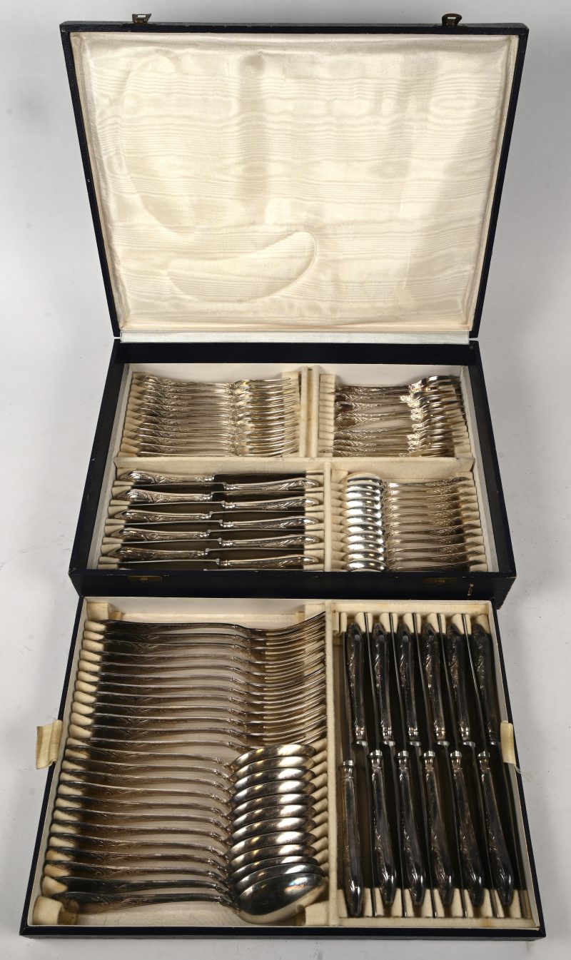 Een 84-delig verzilverd metalen bestek in originele cassette bestaande uit 12 grote lepels, 12 koffielepels, 12 grote vorken, 12 kleine vorken, 12 dessertvorken, 12 grote messen en 12 kleine messen. Gemerkt Alpaca.