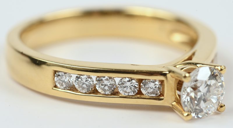 Een 18 kt geelgouden ring bezet met een centrale briljant van +- 0,51 ct. en met briljanten met een gezamenlijk gewicht van +- 0,32 ct.